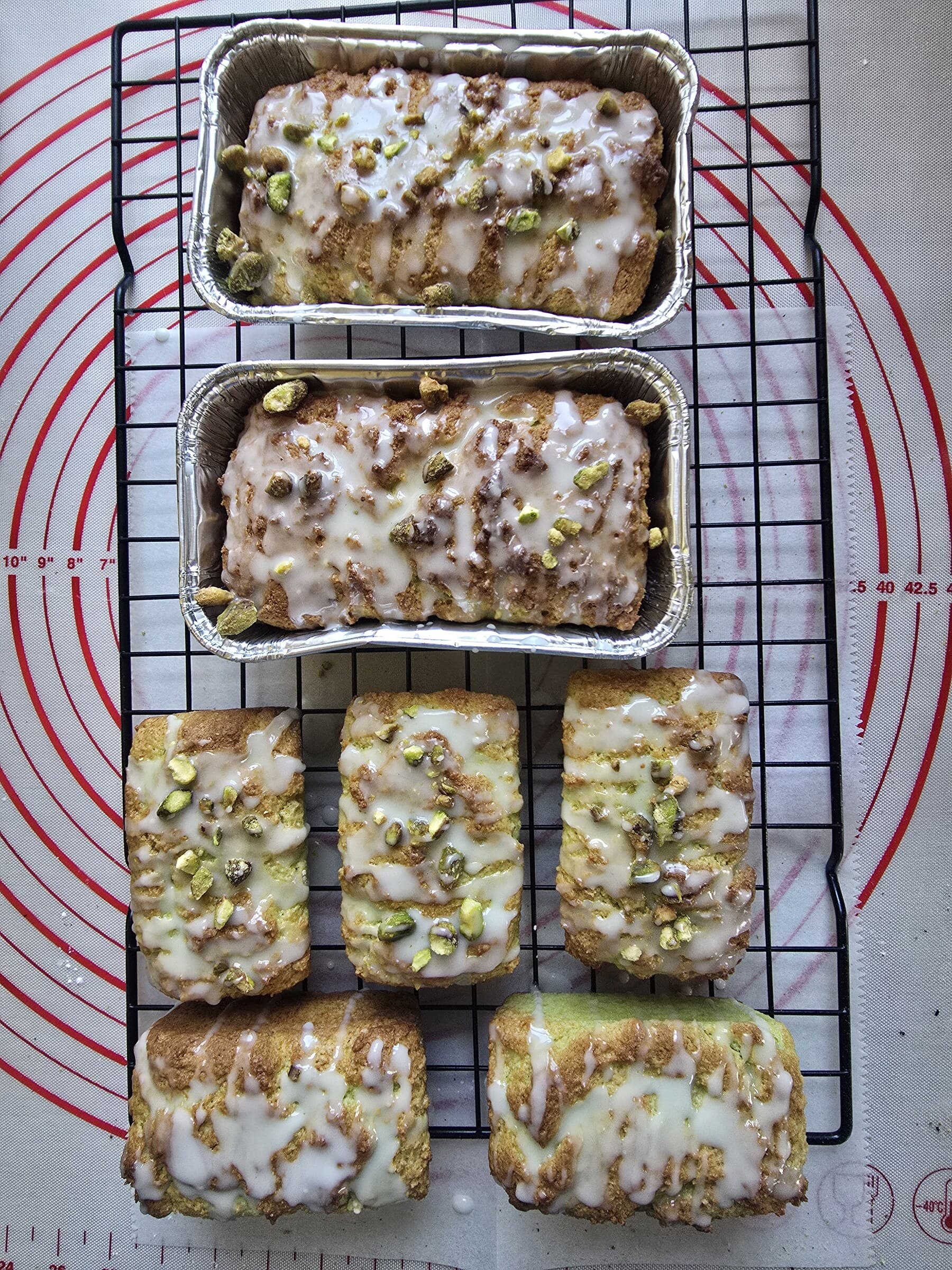 Iced sweet bread loaves and bars cooling together on a wire rack.