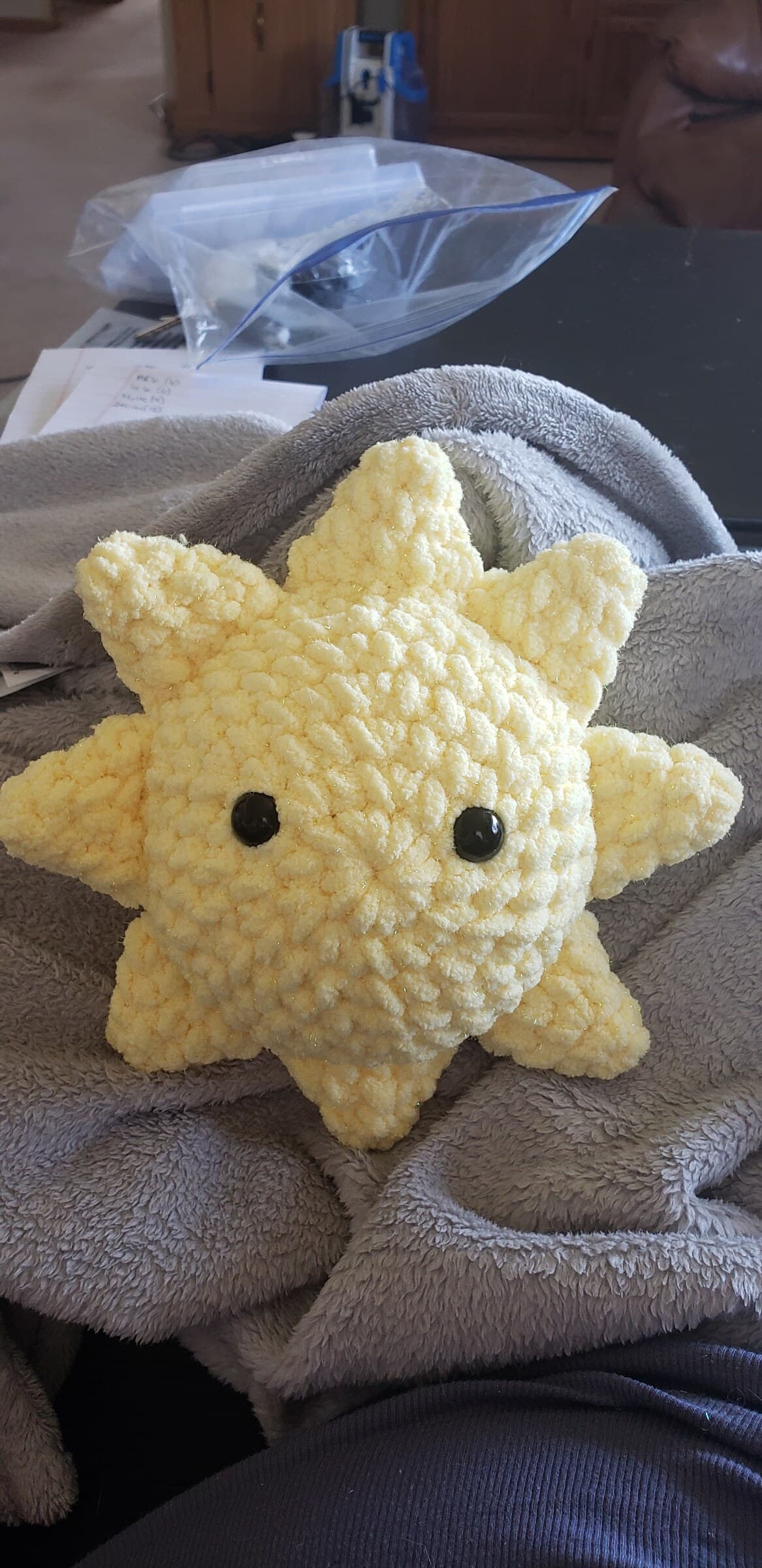 A soft yellow crocheted star plushie with a smiling face.