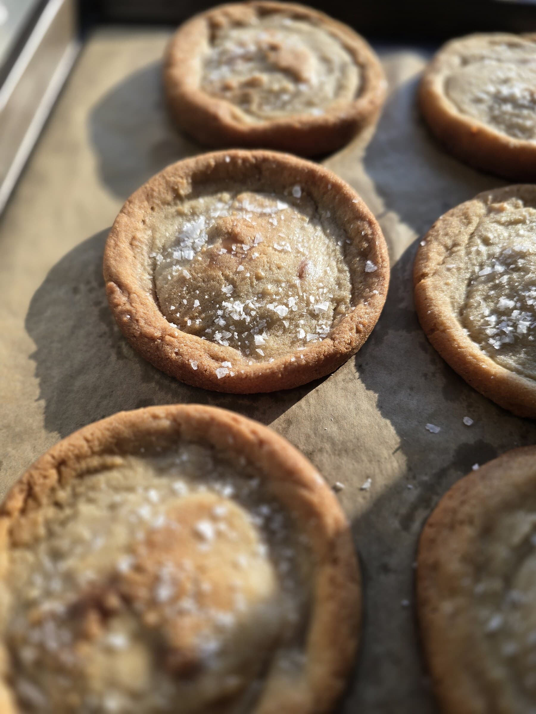A close view of golden filled cookie cups cooling on parchment.