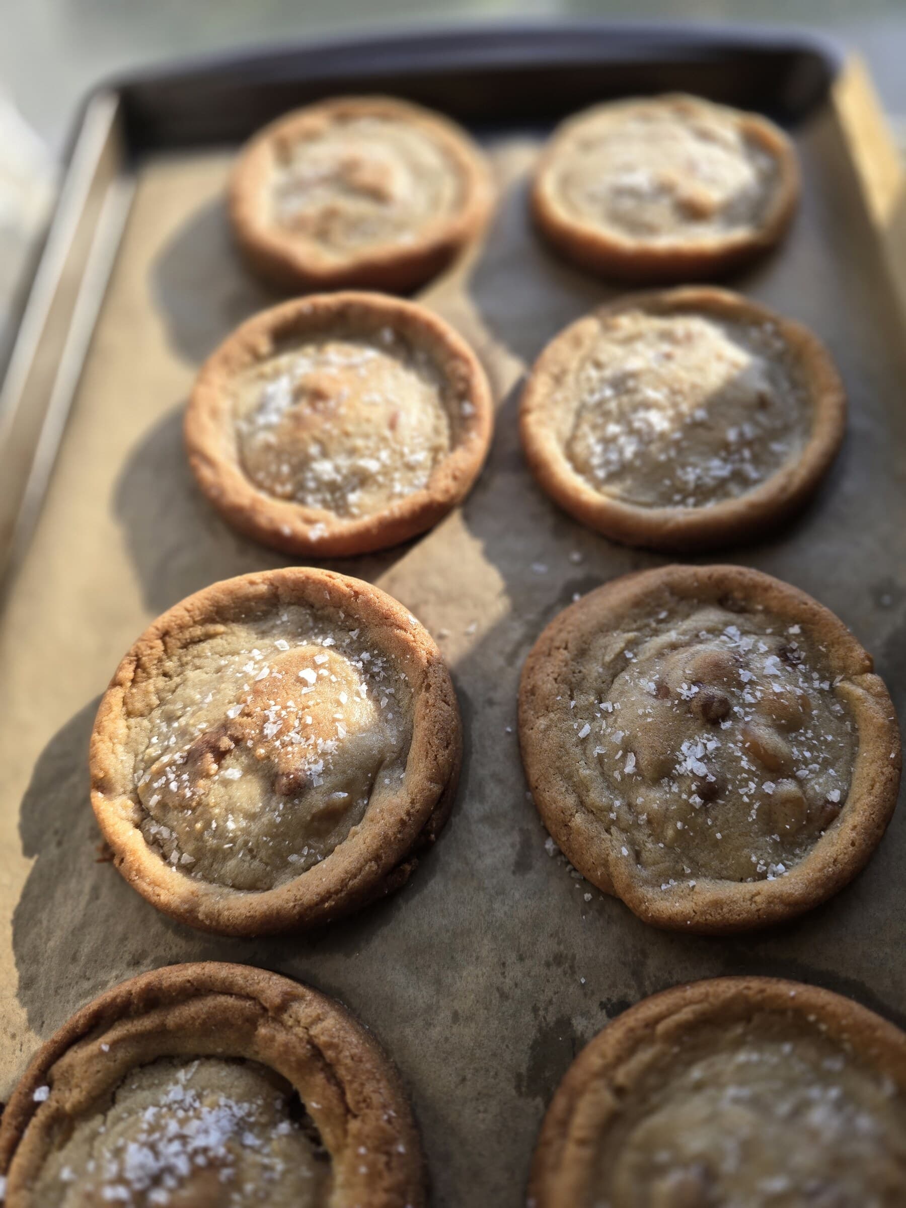 Filled cookie cups arranged on a parchment-lined baking tray.